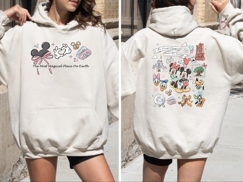 以下が含まれることがあります： 前面にミッキーマウスの耳、ハートを作る手、プレッツェルが描かれたクリーム色のパーカー。「The Most Magical Place On Earth」の文字がプリントされています。パーカーの背面には、さまざまなディズニーのキャラクターやランドマークが描かれています。