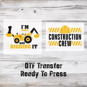 May include: Two designs on white squares. One features a yellow construction vehicle with the text "I'M AND DIGGING IT". The other design has a yellow hard hat and the text "CONSTRUCTION CREW".