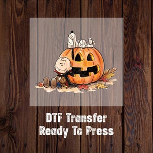 May include: A DTF transfer featuring a cartoon illustration of a character dressed as a vampire sitting next to a large orange jack-o'-lantern with a mummy dog resting on top, surrounded by autumn leaves, with the text DTF Transfer Ready To Press.