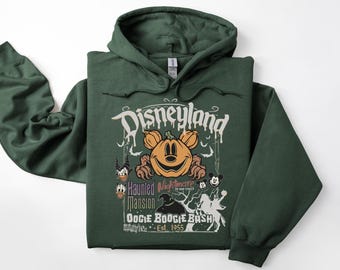 May include: A dark green Disneyland hoodie featuring a Halloween-themed graphic. The design includes a smiling pumpkin, Mickey Mouse, and the text "Haunted Mansion" and "Oogie Boogie Bash". The hoodie has a drawstring hood.