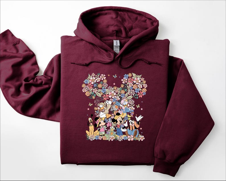 May include: A maroon hoodie featuring a floral Mickey Mouse design. The design includes Mickey, Minnie, Donald, Daisy, Goofy, and Pluto, surrounded by colorful flowers and butterflies. The hoodie has a drawstring hood and long sleeves.