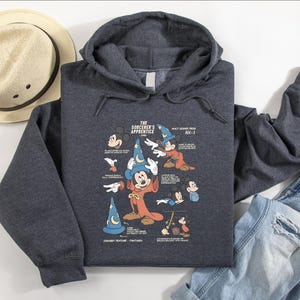 Puede incluir: Una sudadera con capucha gris jaspeado oscuro que presenta un estampado gr&aacute;fico de Mickey Mouse como el aprendiz de brujo. El dise&ntilde;o incluye varios bocetos del personaje, el texto The Sorcerer's Apprentice, Walt Disney Prod y Fantasia.