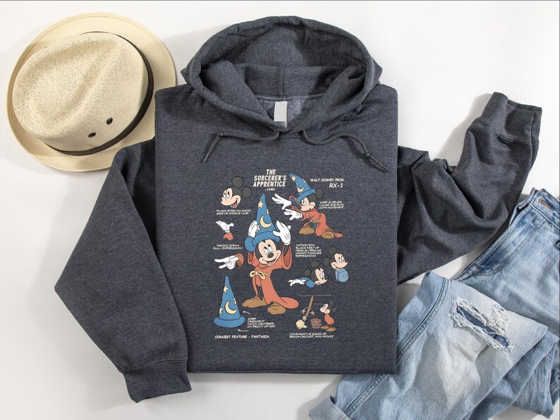 Puede incluir: Una sudadera con capucha gris jaspeado oscuro que presenta un estampado gr&aacute;fico de Mickey Mouse como el aprendiz de brujo. El dise&ntilde;o incluye varios bocetos del personaje, el texto The Sorcerer's Apprentice, Walt Disney Prod y Fantasia.