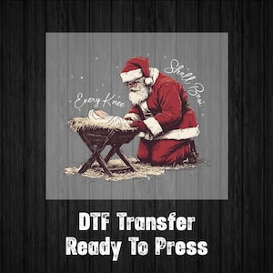 May include: Illustration of Santa Claus kneeling before a baby in a manger. Santa is wearing a red suit and hat. The text reads "Every Knee Shall Bow." Below, the text says "DTF Transfer Ready To Press."