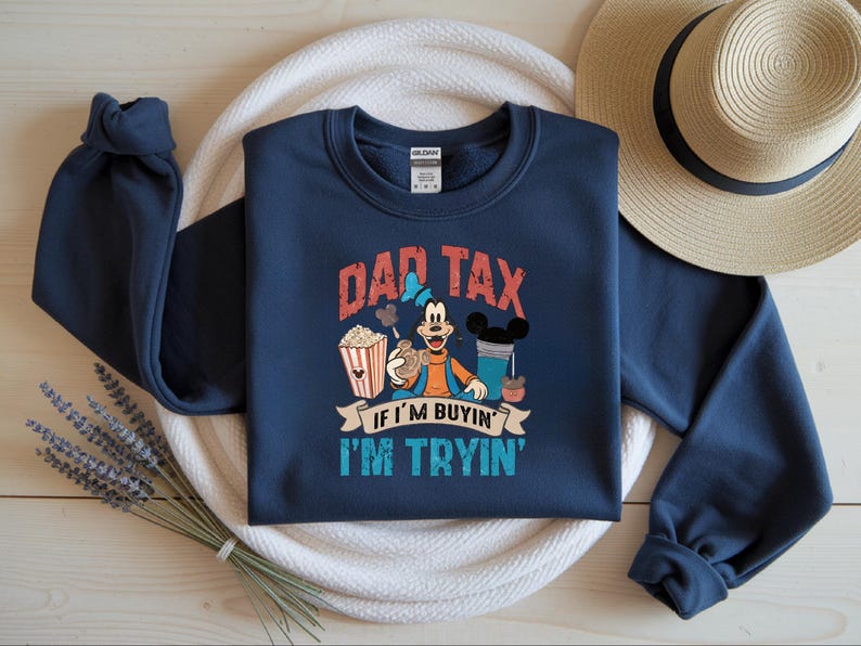 Pode incluir: Uma camisola azul-marinho de manga comprida com um gr&aacute;fico da personagem de desenhos animados Pateta a segurar uma bolacha, ao lado de um balde de pipocas e uma bebida. O texto diz DAD TAX IF I'M BUYIN' I'M TRYIN' em letras vermelhas, brancas e azuis.