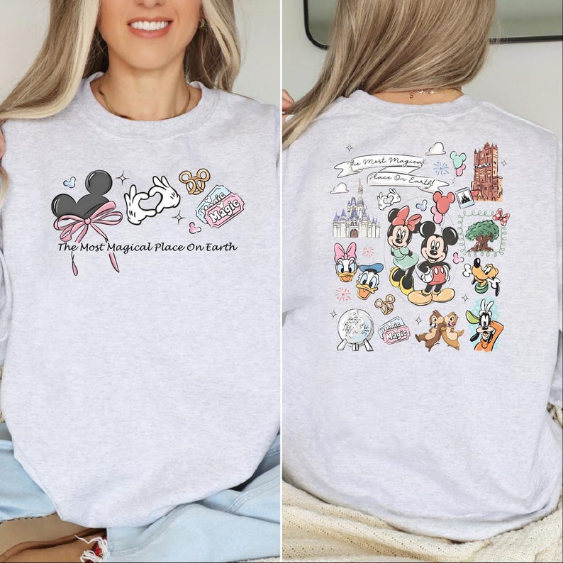 以下が含まれることがあります： ミッキーマウスの耳、ハート型の手、プレッツェルが描かれたライトグレーのスウェットシャツ。「The Most Magical Place On Earth」の文字が前面にプリントされています。背面には、ミッキーとミニーマウスを含む、さまざまなディズニーキャラクターのイラストが描かれています。