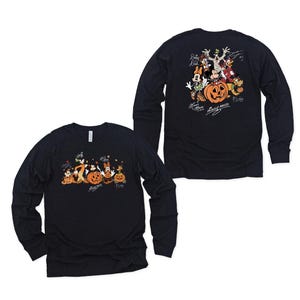 May include: A black long-sleeve shirt featuring a graphic of Disney characters with pumpkins. The front shows the characters in a line, while the back displays them in a group with signatures. The print includes Mickey Mouse, Minnie Mouse, Goofy, Donald Duck, Daisy Duck, and Pluto.