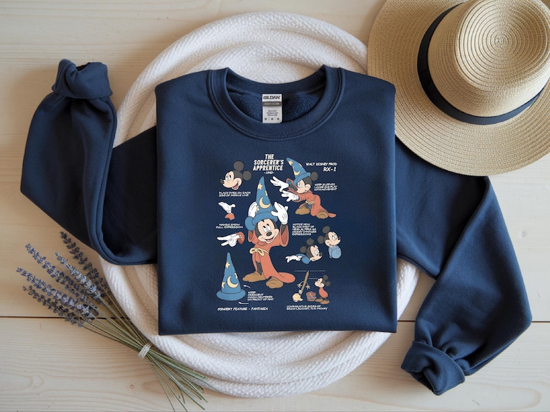 Puede incluir: Una sudadera azul marino de manga larga con un estampado gr&aacute;fico de Mickey Mouse como el aprendiz de brujo. El dise&ntilde;o incluye varios bocetos del personaje y el texto The Sorcerer's Apprentice, Walt Disney Prod y RX-1.