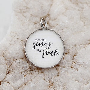 May include: A silver charm with a white background and the text "then sings my soul."