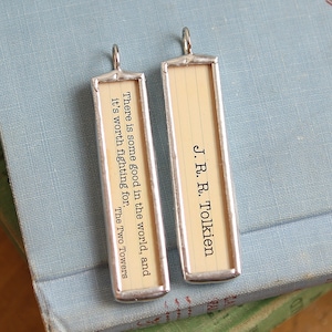 May include: Two rectangular pendants with silver-colored frames. One pendant has the text "There is some good in the world, and it's worth fighting for. The Two Towers." The other pendant reads "J.R.R. Tolkien."