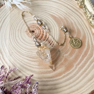 May include: A gold chain with clear crystal beads and a gold pentagram charm attached to a clear quartz crystal pendulum with gold flecks.