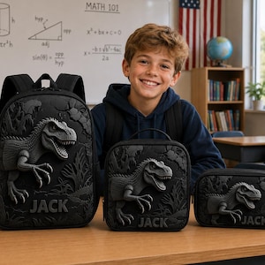 May include: A black backpack, a square lunch bag, and a rectangular pencil case, all featuring a raised 3D dinosaur design and the name JACK embossed on the front. Each item is constructed from a dark material with a textured prehistoric jungle scene.