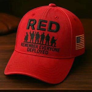 May include: A red baseball cap with the word "RED" embroidered in black on the front. Below the word are silhouettes of soldiers and the text "REMEMBER EVERYONE DEPLOYED." An American flag patch is on the side.