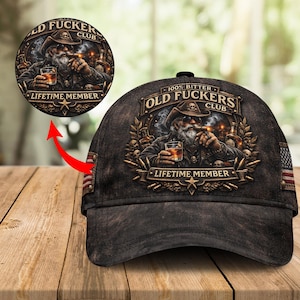May include: A black baseball cap with a distressed look, featuring a detailed graphic of an old man with a beard, cowboy hat, and cigar, holding a drink. The text reads "OLD FUCKERS CLUB" and "LIFETIME MEMBER".