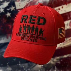 May include: A red baseball cap with the word "RED" in black block letters. Below the word are black silhouettes of soldiers and the text "REMEMBER EVERYONE DEPLOYED." An American flag patch is on the side.