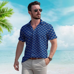 Puede incluir: Una camisa azul de manga corta con un patr&oacute;n geom&eacute;trico de formas grises. La camisa tiene cuello y se combina con pantalones de color claro y un cintur&oacute;n marr&oacute;n. El fondo presenta una escena de playa con palmeras y cielo azul.