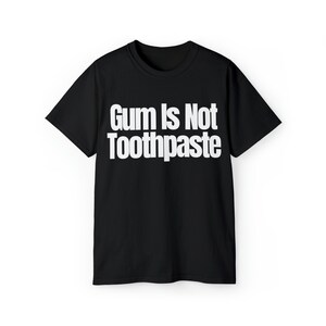 Op de afbeelding: Zwart T-shirt met witte tekst die "Gum Is Not Toothpaste" zegt.