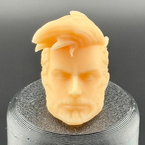 May include: A light brown plastic head sculpt with a sculpted hairstyle and beard. The head is designed for use with action figures.