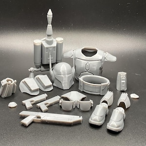 May include: A set of 3D printed Mandalorian armour pieces, including a helmet, chest plate, jetpack, and various other accessories. The pieces are all grey and appear to be made of plastic.