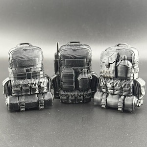 以下が含まれることがあります： 複数のポケットとストラップが付いた、黒い戦術用バックパック3つ。バックパックは耐久性のある防水素材で作られています。