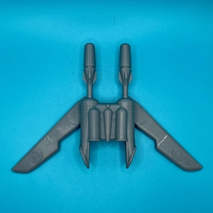 Peut inclure: Un vaisseau spatial jouet en plastique gris avec deux moteurs et des ailes. Le vaisseau spatial a un design détaillé avec un cockpit et une section arrière.