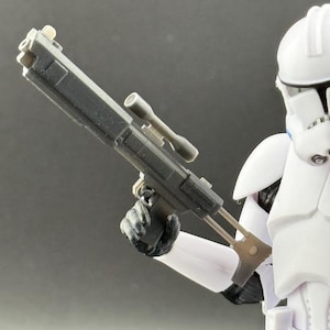 May include: A black plastic blaster with a scope and a white Stormtrooper action figure holding the blaster.