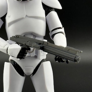May include: A white action figure of a stormtrooper holding a black blaster rifle.