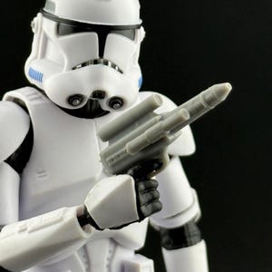 Peut inclure: Figurine d'un Stormtrooper blanc tenant un blaster gris. Le casque blanc a des d&eacute;tails noirs et bleus. Le blaster est tenu dans la main droite. Objet de collection.