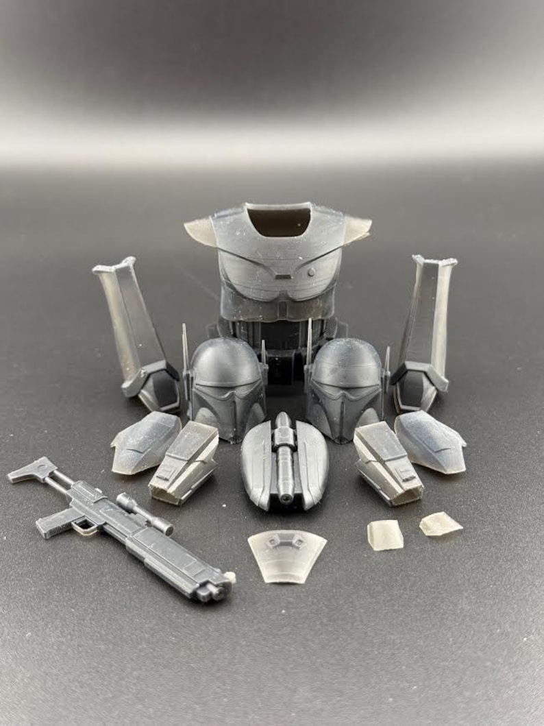 May include: A set of black plastic action figure armour pieces, including a chest piece, helmet, and shoulder pads. The armour is designed to look like a futuristic warrior's armour. There is also a black plastic blaster rifle and a clear plastic visor.