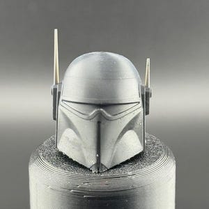 May include: A black plastic helmet with two small antennas on top. The helmet has a visor and a textured surface.