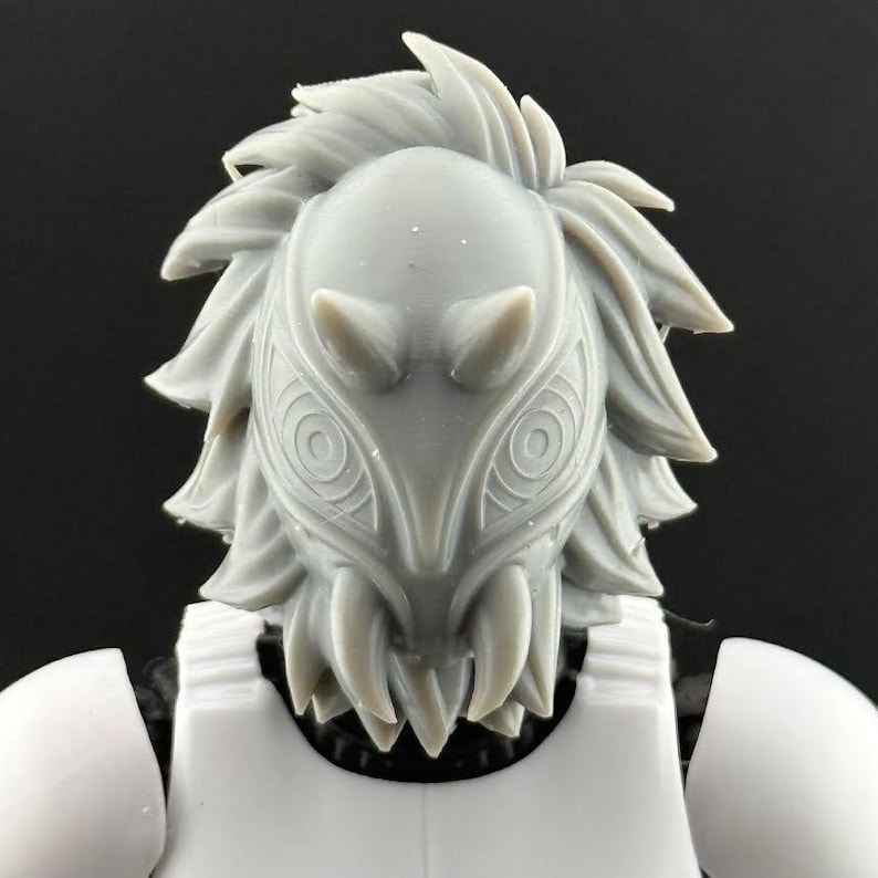May include: A gray, detailed mask with a stylized design, featuring sharp teeth and intricate patterns. The mask is part of a larger figure, with white armor visible below. The overall aesthetic suggests a fantasy or sci-fi theme.
