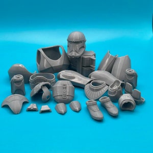 Peut inclure: Un ensemble de pièces en plastique gris imprimées en 3D pour une figurine de modèle. Les pièces comprennent un casque, un torse, des bras, des jambes et d'autres accessoires.