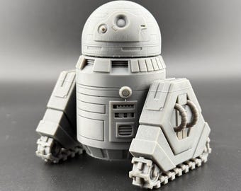 May include: A gray, 3D printed robot toy with a round head and a detailed body. The robot has a series of wheels on the bottom and a panel on the front with a series of buttons and a small window.