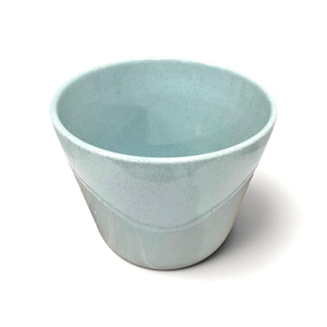 May include: A conical ceramic bowl featuring a speckled light blue glaze on the upper portion and a smooth, unglazed matte finish on the lower section. The interior is finished with the same speckled light blue glaze as the exterior rim.