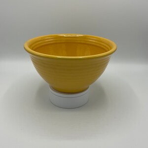 May include: A yellow ceramic mixing bowl with a smooth, glossy finish. The bowl has a rounded shape and a wide rim.