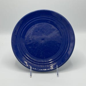 May include: A deep blue ceramic plate with a slightly raised rim and concentric circles in the center.