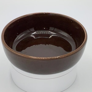 May include: A brown ceramic bowl with a white base. The bowl is empty and has a smooth, glossy finish.