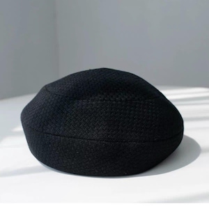 May include: A solid black beret featuring a distinct, uniform textured knit pattern across its entire surface. The hat has a rounded, circular crown and a structured, slightly raised band that encircles the base, maintaining a consistent shape.