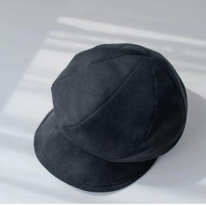 Puede incluir: Un sombrero negro redondo de tela con un ala ancha. El sombrero tiene una superficie ligeramente texturizada.