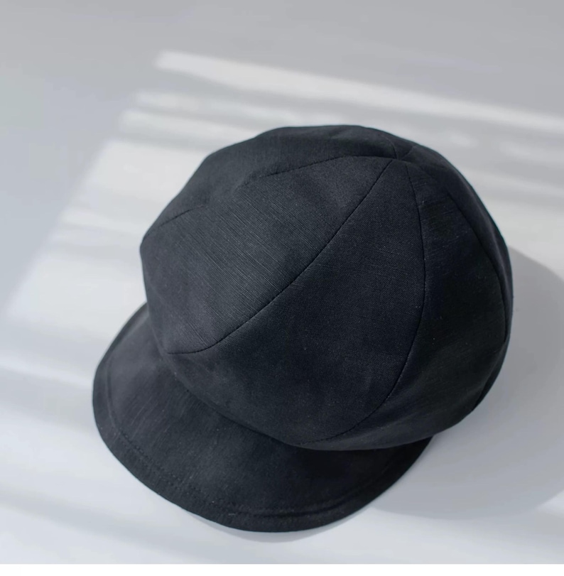 Puede incluir: Un sombrero negro redondo de tela con un ala ancha. El sombrero tiene una superficie ligeramente texturizada.