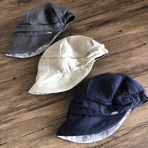 May include: Three reversible hats in different colors. The hats are made of a soft, linen-like fabric. The hats are all folded in the same way, with the top of the hat folded down to create a brim. The hats are all reversible, with a floral pattern on the inside.