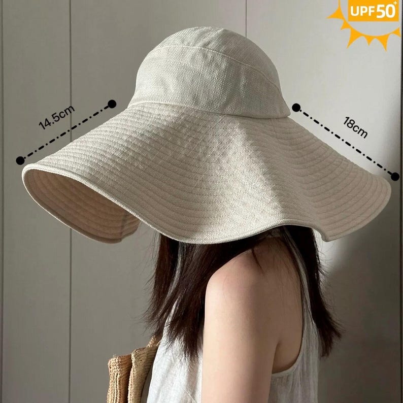 May include: A beige sun hat with a wide brim, approximately 7 inches wide, and a UPF 50 rating. The hat's brim is 5.7 inches long. The hat is made of a woven material and has a rounded crown. The hat is designed to provide sun protection.