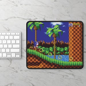 Op de afbeelding: Een blauw en rood videogamepersonage, Sonic the Hedgehog, rent over een groen en bruin landschap. De achtergrond is een blauwe lucht met palmbomen. De tekst "SONIC" en "3" staan in de rechterbovenhoek van de afbeelding.