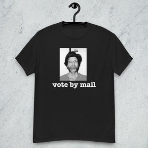 May include: Black t-shirt with a black and white photo of a man with the text "vote by mail" in white.