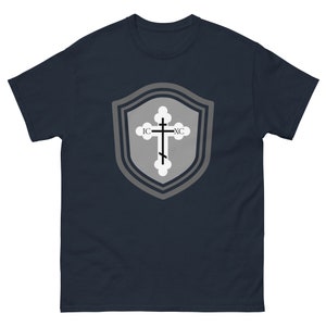 May include: A navy blue t-shirt with a gray shield design featuring a white cross with the text "IC XC" on it.