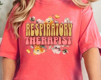 Puede incluir: Una camiseta rosa con estampado floral y el texto "Respiratory Therapist" en una fuente retro.