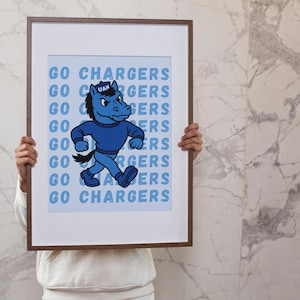 May include: Framed poster featuring a blue cartoon horse mascot with the text "GO CHARGERS" repeated in a light blue font. The horse is wearing a blue sweater and is walking. The frame is brown.