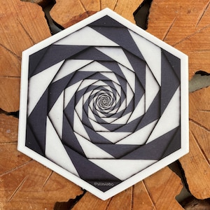 May include: A black and white hexagonal sticker with a spiral pattern. The sticker has a white background with black lines creating a spiral effect. The sticker has the text "@stasiabo" at the bottom.