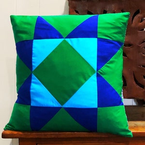 May include: A green, blue and turquoise patterned cushion with a geometric design.