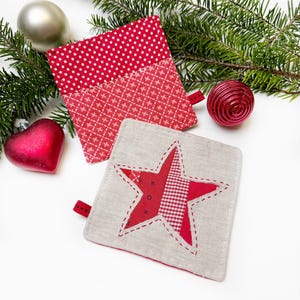 May include: Two red and white Christmas-themed pot holders. One is a square with a red and white polka dot pattern and a red and white checkered pattern. The other is a square with a beige linen background and a red star made of patchwork fabric.